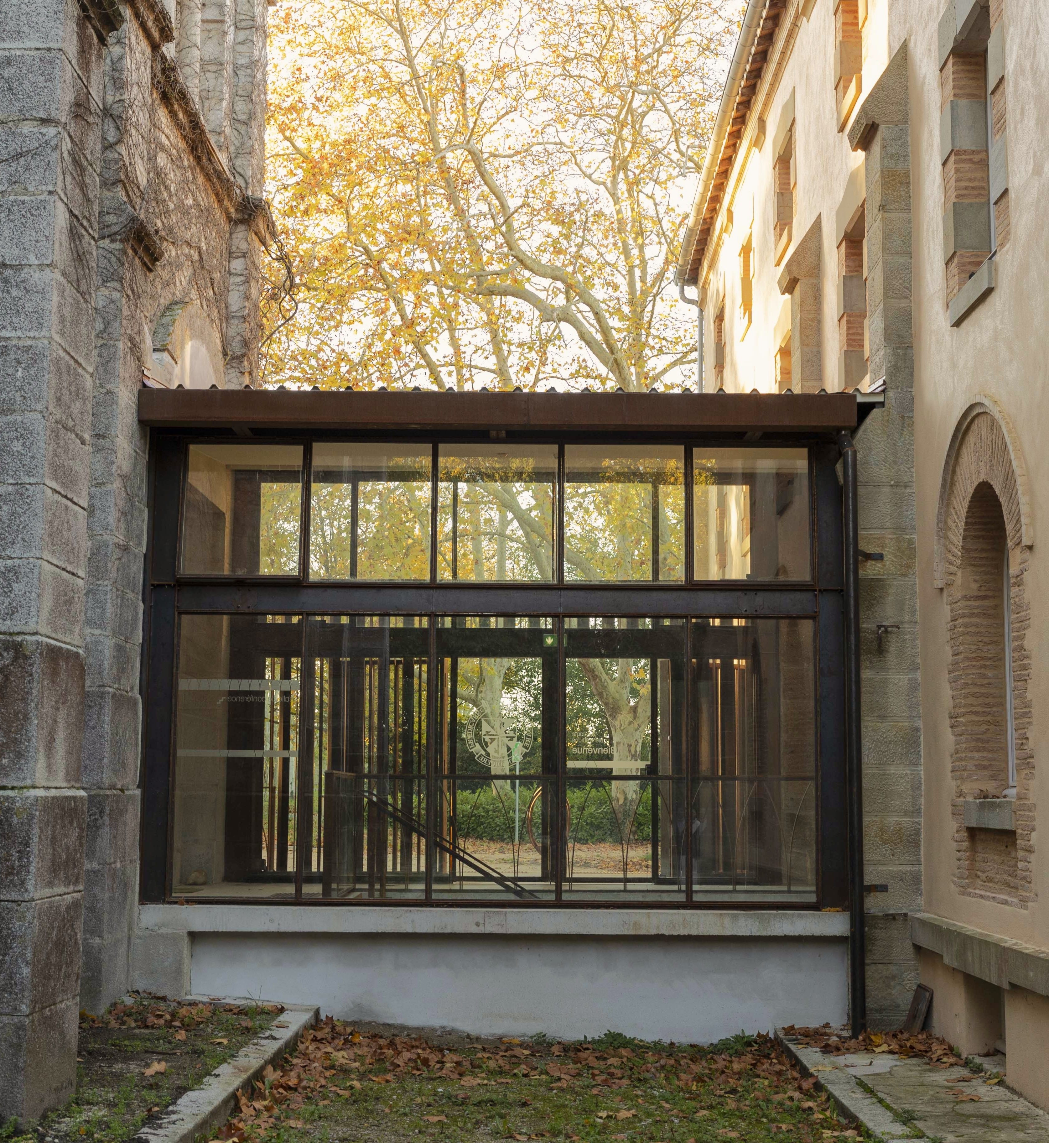 Extension contemporaine en verre et acier greffée sur un bâtiment ancien en pierre