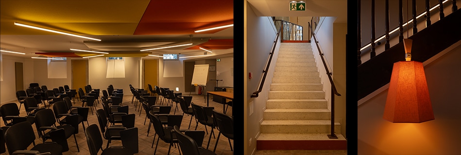 Salle de séminaire aux disques acoustiques colorés au plafond, escalier en terrazzo et applique en tissu orange