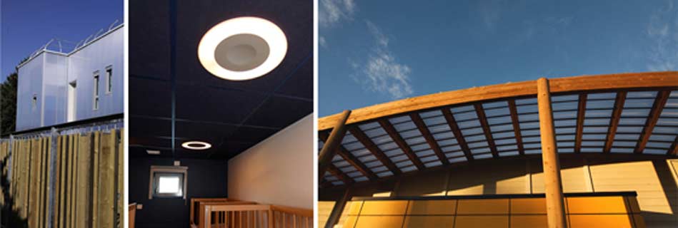 Volume translucide en façade, plafond acoustique sombre percé d'un puits de lumière rond, et pergola bois à couverture translucide au soleil