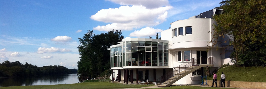 L'ensemble blanc du restaurant au bord de la Garonne en journée, sa rotonde vitrée sur pilotis et son escalier extérieur